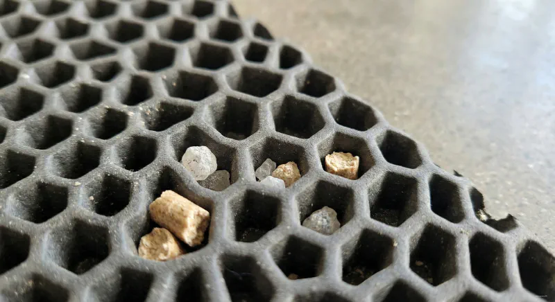 Macro close-up of a honeycomb litter trapping mat with coarse litter particles caught in the texture